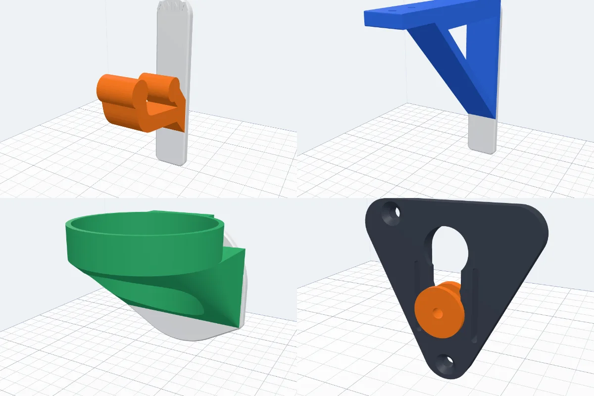 Four 3D printed wall mounts: an orange coat hook on a white plate, a blue shelf bracket, a green cup ring and a slot plate with an orange printed button